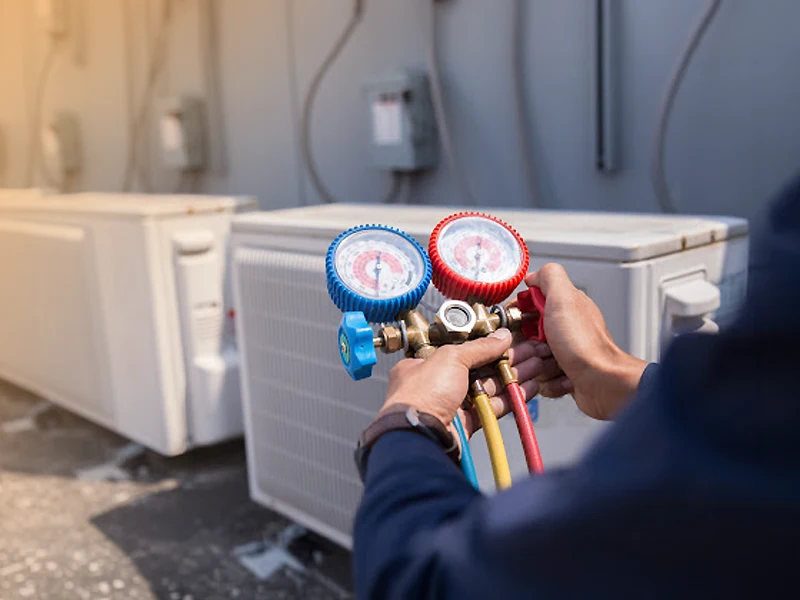 AC technician checking refrigerant gauges on HVAC unit — AC service Abu Dhabi Musaffah